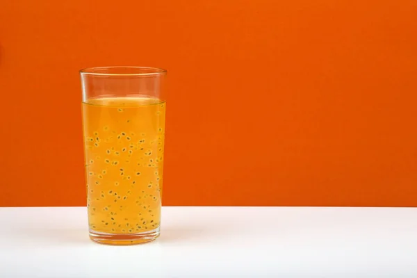 Färsk fruktjuice med passionsfrukt frö på vitt bord mot orange bakgrund med utrymme för text — Stockfoto
