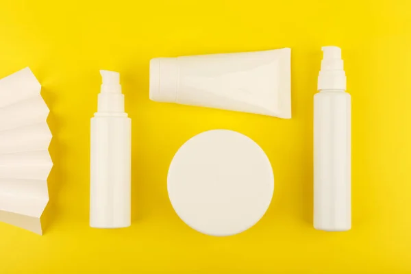 Conjunto de variedade de produtos cosméticos skincare em frascos brancos sem marca sobre fundo amarelo — Fotografia de Stock