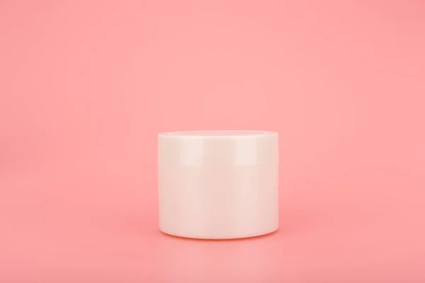 Einfaches Stillleben mit weißem Glas mit Maske, Creme oder Balsam auf rosa Tisch vor rosa Hintergrund mit Kopierraum — Stockfoto