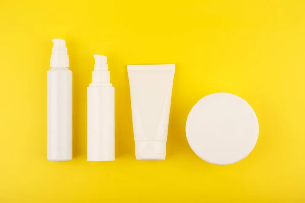 Colocação plana com conjunto de produtos cosméticos para cuidados com a pele e o corpo no fundo amarelo brilhante — Fotografia de Stock