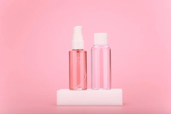 Reinigungsschaum oder -gel und feuchtigkeitsspendende Hautlotion in transparenter Flasche auf weißem Podium vor leuchtend rosa Hintergrund — Stockfoto
