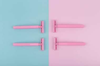 Pembe ve mavi arka planda dört pembe plastik ustura ile düz yatıyordu.