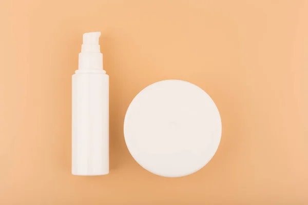 Deitado plano minimalista com tubo branco sem marca com creme facial ou gel e frasco redondo branco com máscara ou bálsamo. — Fotografia de Stock