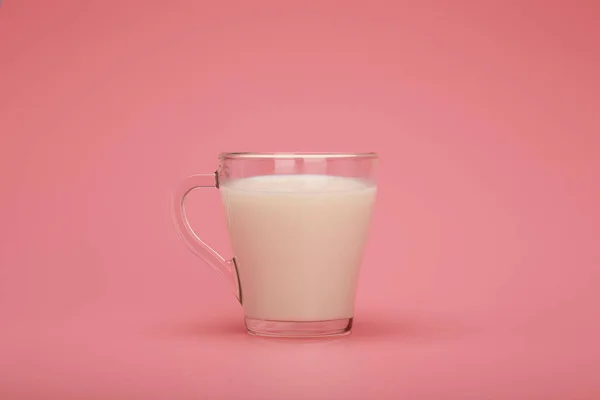 Taza transparente con leche sobre fondo rosa con espacio para copiar — Foto de Stock