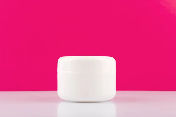 Frasco de creme branco na mesa branca brilhante contra fundo rosa com espaço de cópia. Conceito de beleza e cuidados com a pele — Fotografia de Stock