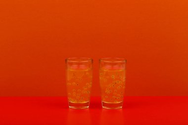 Kırmızı masada kırmızı zemin üzerinde meyve alkollü iki shot ve fotokopi alanı. Gece hayatı ve bar kavramı