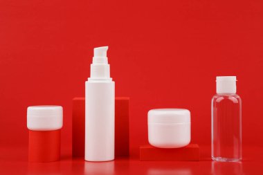 Geometrik destekli kırmızı arka plana karşı güzellik ürünleri seti. Güzellik anlayışı ve günlük cilt bakımı 