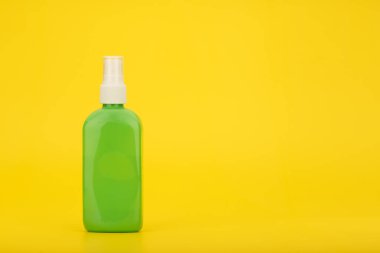 Sunscreen spray against yellow background with copy space. Sunscreen product for tanning in green plastic tube.