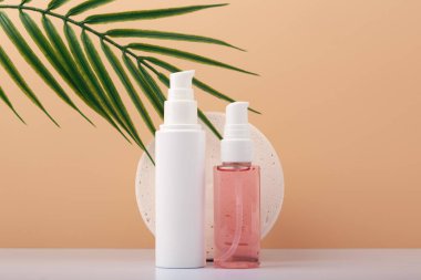 Cilt bakım kremi ve temizleyici köpük, arka planda bej ve palmiye yaprağı. Kadınlar için güzellik ürünleri