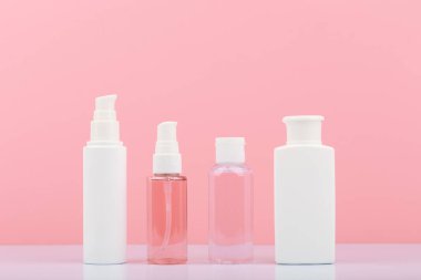 Cilt temizleme, deri yüzme ve nemlendirme için kozmetik ürünler. Pembe arka plana karşı kozmetik şişeler