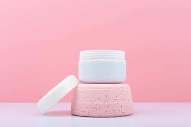 Beyaz, pembe kürsüde açık kozmetik kavanozu ile fotokopi alanı ile parlak pembe arkaplan karşı karşıya