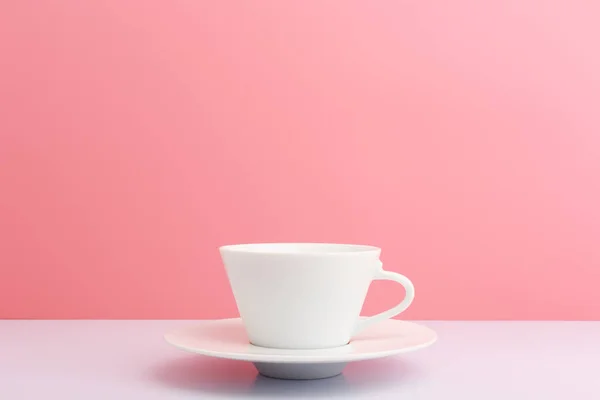 하얀 세라믹 커피 컵에 접시가 있는 하얀색 탁자 위에 복사 공간 이 있는 밝은 핑크 색 배경 — 스톡 사진