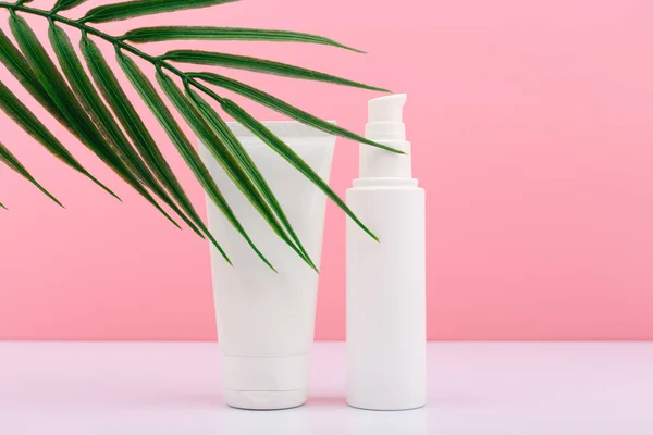 Two white unbranded cream tubes against pink background with palm leaf — Stock Photo, Image