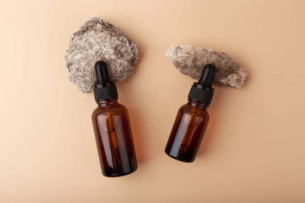 Top view of two bottles with skin serums on stones at beige background — Stock Photo, Image