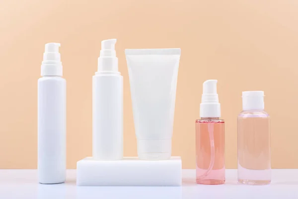 Kosmetikflaschen-Set für die tägliche Hautpflege auf weißem Tisch vor hellbeigem Hintergrund. — Stockfoto