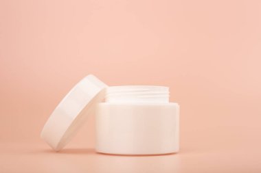 Bej arka planda kozmetik krem kutusu açıldı. Cilt bakımı için güzellik ürünleri kavramı. 