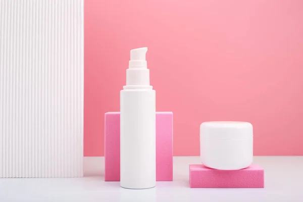 Set aus Kosmetikschlauch und Glas vor rosa Hintergrund und weißer Wand mit Streifen — Stockfoto