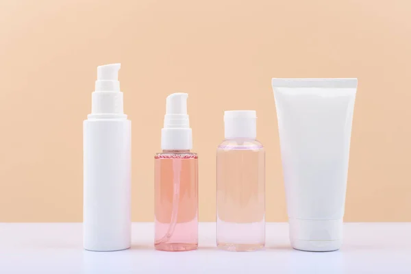 Kosmetikflaschen für die tägliche Hautpflege vor hellbeigem Hintergrund. — Stockfoto
