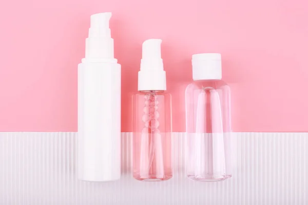 Set aus Kosmetiktuben und Glas vor rosa Hintergrund und weißem Papier mit Streifen — Stockfoto