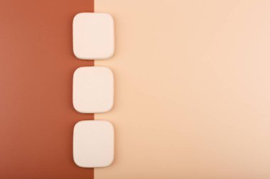 Bej ve kahverengi arka planda üç makyaj süngerinin üst görüntüsü. Farklı ten renkleri kavramı