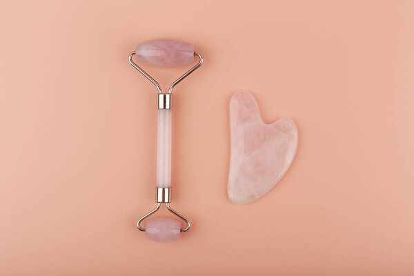 Вид сверху нефритовой розы и маскарада в форме сердца из розового кварца на бежевом фоне. Гуашский массаж