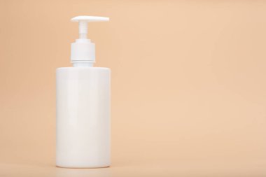 Duş jeli ya da uzun beyaz plastik tüplü kadın için özel jel. Bej arka planda fotokopi alanı olan.