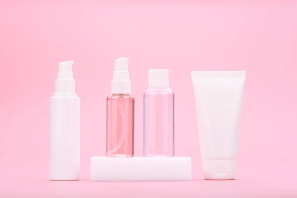 Açık pembe arka plana karşı günlük akne karşıtı cilt tedavisi için güzellik ürünleri.