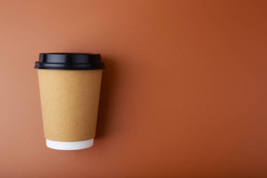 Kahverengi zemin üzerinde karton kahve fincanı ve fotokopi alanı ile düz yatıyordu.