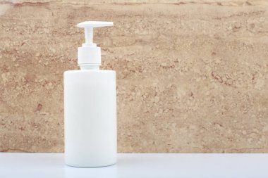 Duş jeli ya da banyodaki sıvı sabun bej mermer duvara karşı metin için yeri var.