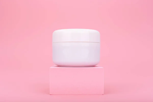 Frasco de creme branco no pódio rosa no fundo rosa brilhante — Fotografia de Stock