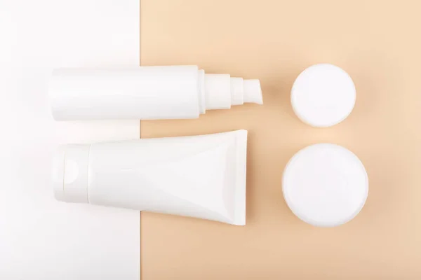 Płaska leżanka z zestawem kosmetyków do codziennej pielęgnacji skóry na białym i beżowym tle — Zdjęcie stockowe