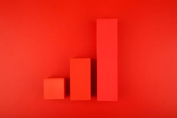 Top view of increasing chart made of red blocks on red background. Concept of business, sales and increasing dynamics