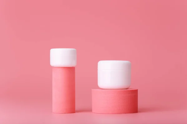 Trendy pink set of cosmetic jars on geometric shapes against pink background — Stock Photo, Image