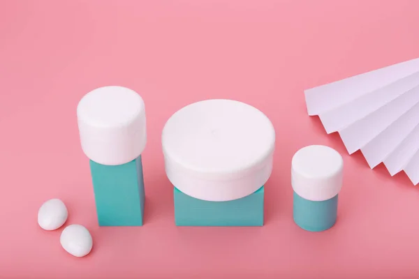 Composição criativa com produtos de cuidados da pele sobre fundo rosa decorado com pedras brancas e vacilante — Fotografia de Stock