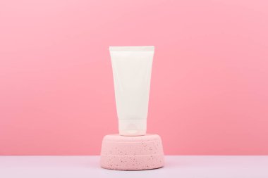 Krem, merhem, maske, pembe kaidedeki krem veya losyon ile pembe arka planda fotokopi alanı olan beyaz plastik kozmetik tüp. Doğal organik cilt bakım ürünleri kavramı 
