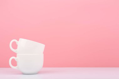 Beyaz seramik bardağı, pembe arkaplanla fotokopi alanı arasında kapatıyoruz. Sıcak içecekler ve mutfak eşyaları kavramı
