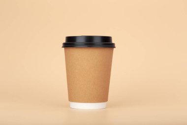 Kahverengi karton bardağı çay ya da pastel bej arka planda kahve ile kapatın. Atıştırmalık sıcak içecek kavramı, minimum basit kompozisyon