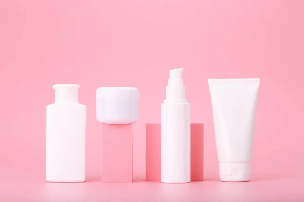 Parlak pembe arkaplana karşı geometrik aksesuarlarda güzellik ürünleri bulunan pembe renkli kozmetik şişeler. Anti akne kavramı ya da düzenli temel deri tedavisi