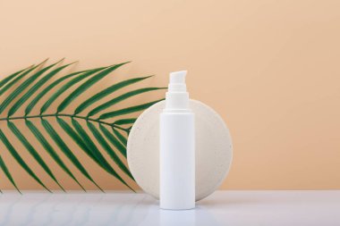 Beyaz kozmetik tüpü, krem, merhem, fırça ya da manikür için kullanılacak ürün, arka planda bej, palmiye yaprağı ve fotokopi alanı var. Manikür, el ve yüz için doğal organik cilt bakım ürünleri kavramı