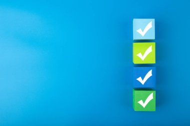 Renkli küplerin üzerindeki dört işaret fotokopi alanı ile parlak mavi arkaplanı karşılaştırıyor. Sorgulama, kontrol listesi, yapılacaklar listesi, planlama, işletme veya doğrulama için asgari eğilim kavramı