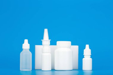 İlaç hapları, kulak damlaları, göz damlaları ve mavi arka planda fotokopi alanı olan burun spreyi. Soğuk algınlığına bağlı hastalıkların tedavisi ve baca temizliği kavramı