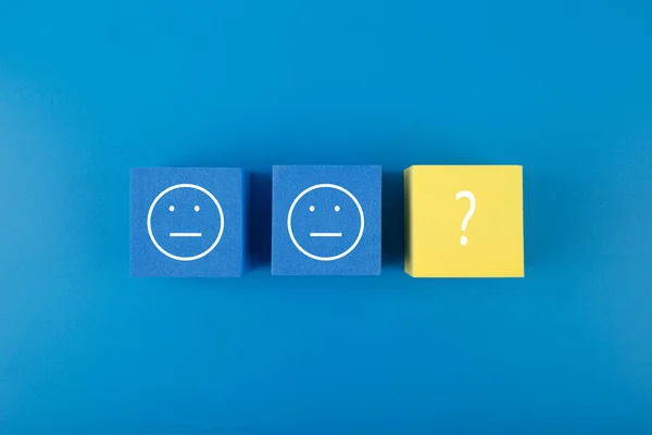 Zihinsel ve psikolojik sorunlar için tedavi ve çözüm olarak emoji içeren mavi ve sarı küpler. Mavi renkte minimal modern akıl sağlığı kavramı