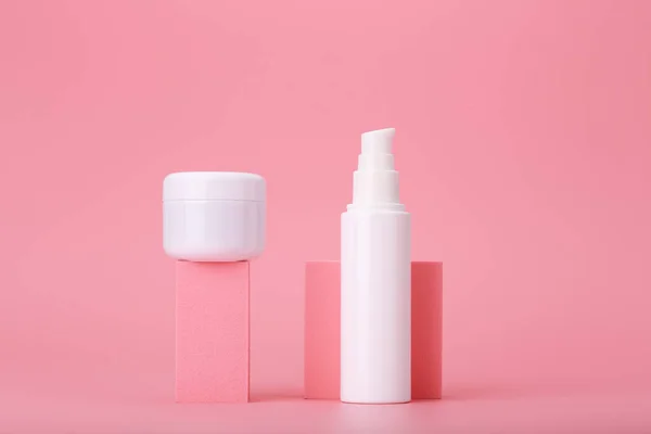 Composição na moda com conjunto de frascos de cosméticos em formas geométricas contra fundo rosa — Fotografia de Stock