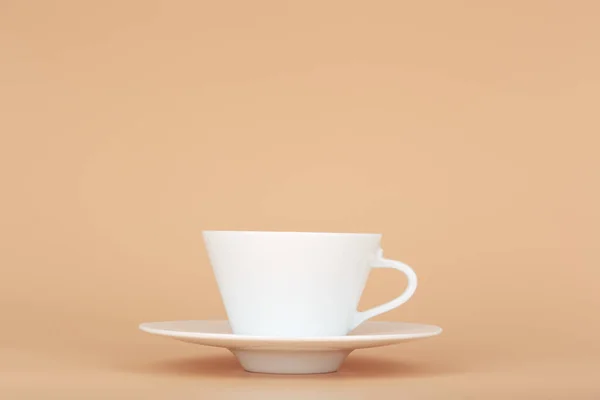 带有茶托的白色陶瓷咖啡杯 衬托着柔和的米色背景 有复制空间 热饮料 陶瓷杯和厨房用具的概念 — 图库照片