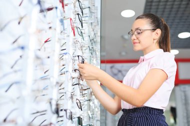 Kadın gözlüğü optik mağazasında, görme ve görme konseptinde seçiyor.