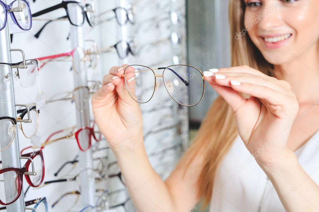 Woman choosing the glasses in optics store, eyesight and vision concept