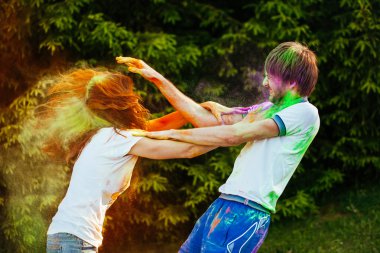 genç ve güzel bir çift holi renkli fes parkta oynarken