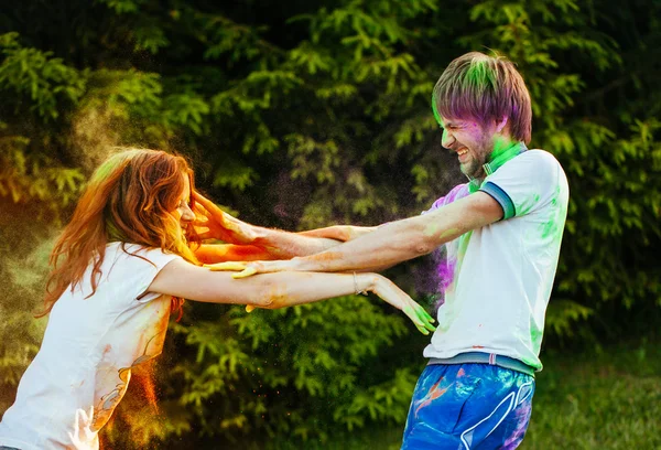 Jovem e belo casal brincando no parque em holi cor fes — Fotografia de Stock