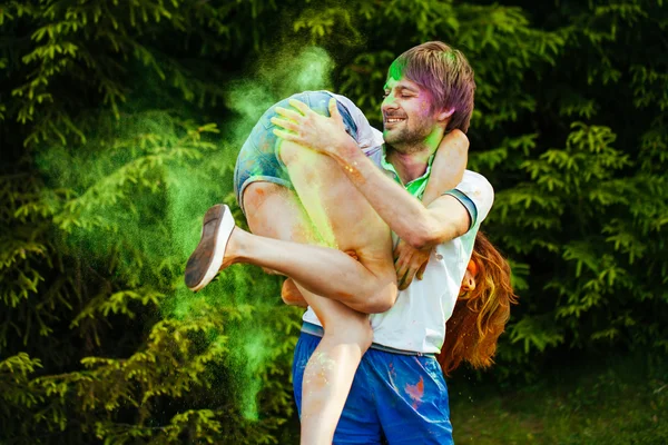 Jovem e belo casal brincando no parque em holi cor fes — Fotografia de Stock