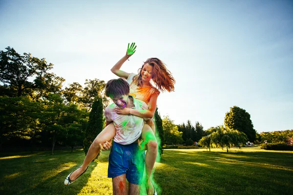 Jovem e belo casal brincando no parque em holi cor fes — Fotografia de Stock